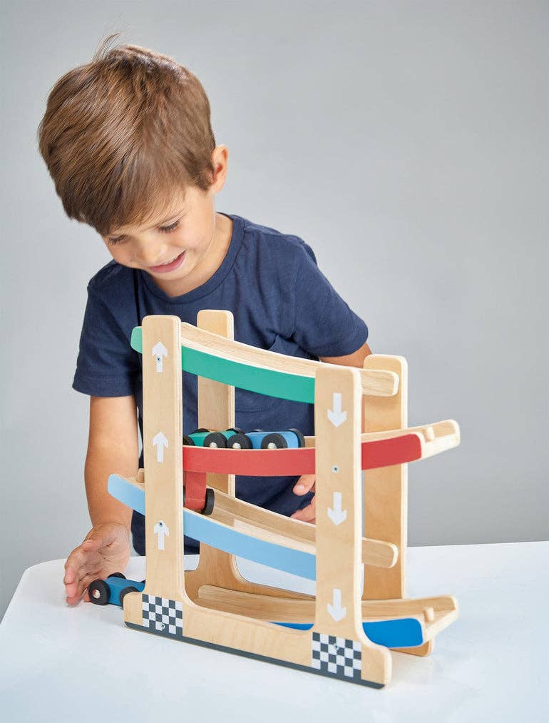 
                  
                    Child playing with a wooden toy track set against a gray background.
                  
                