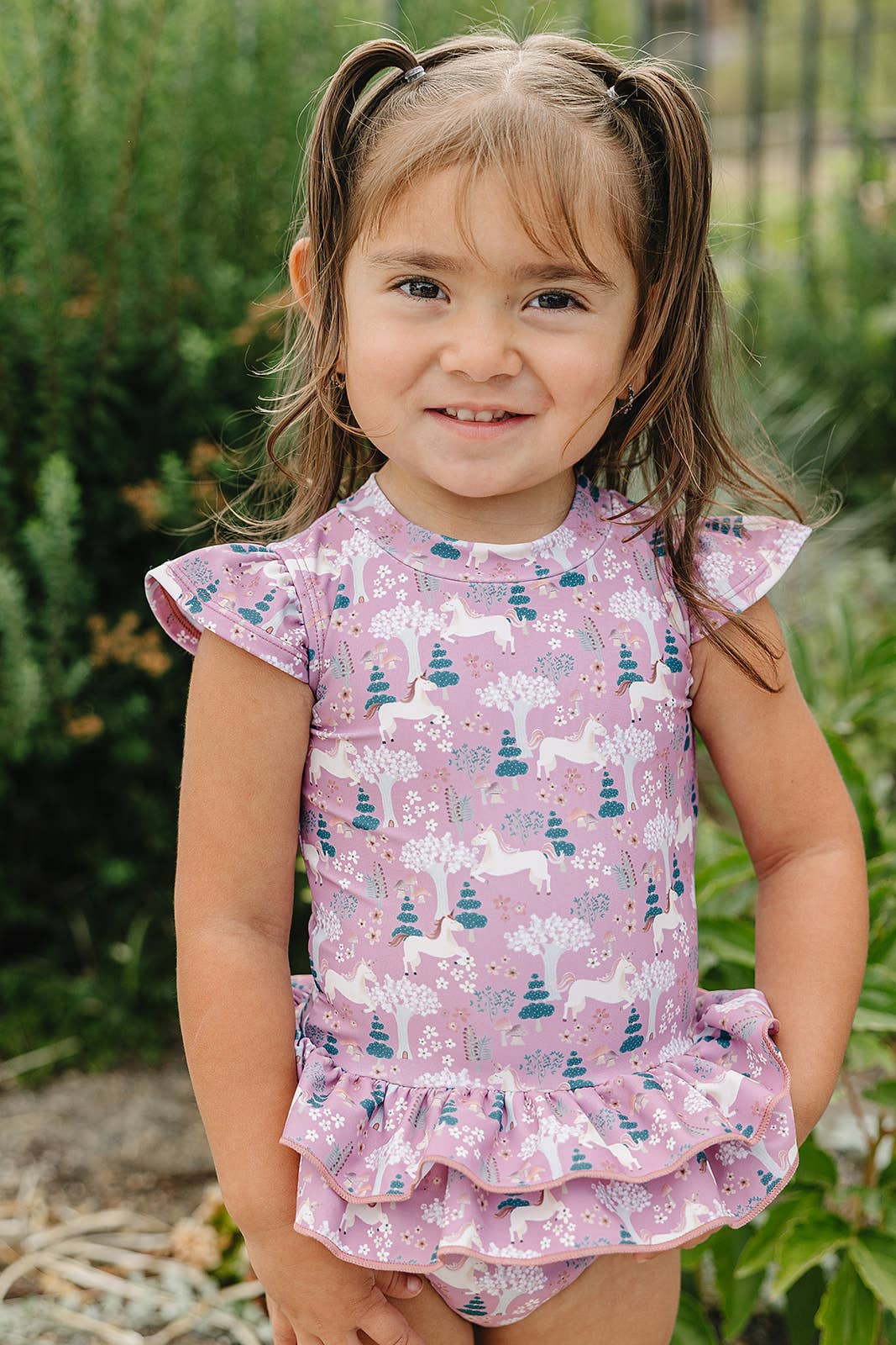 
                  
                    Young girl wearing a pink swim outfit with animal prints in an outdoor setting
                  
                