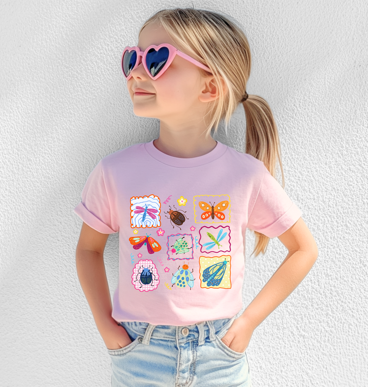 
                  
                    Child wearing a pink t-shirt with colorful butterfly designs against a white wall.
                  
                