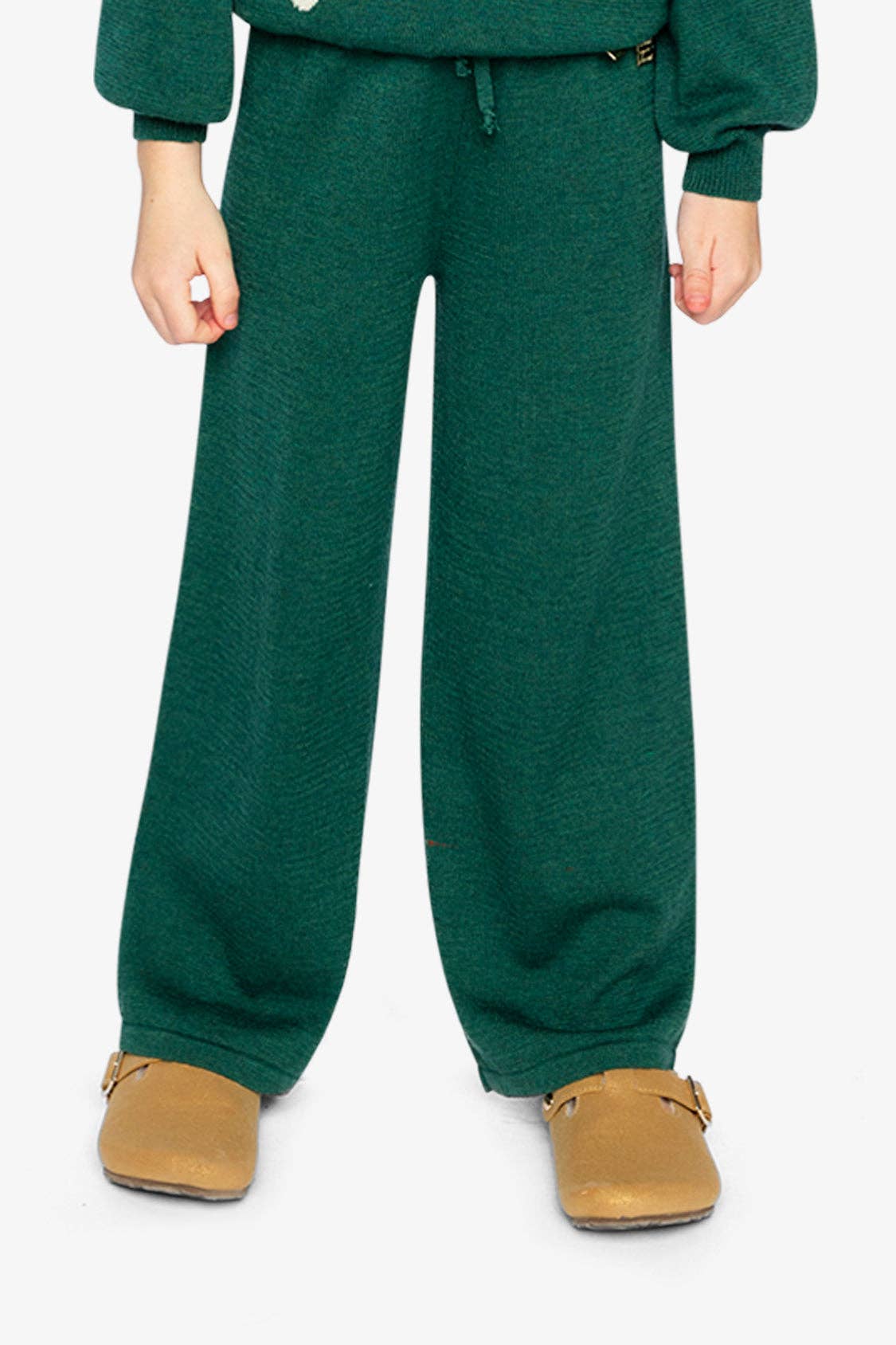
                  
                    Person wearing a green outfit with wide-leg pants on a white background.
                  
                