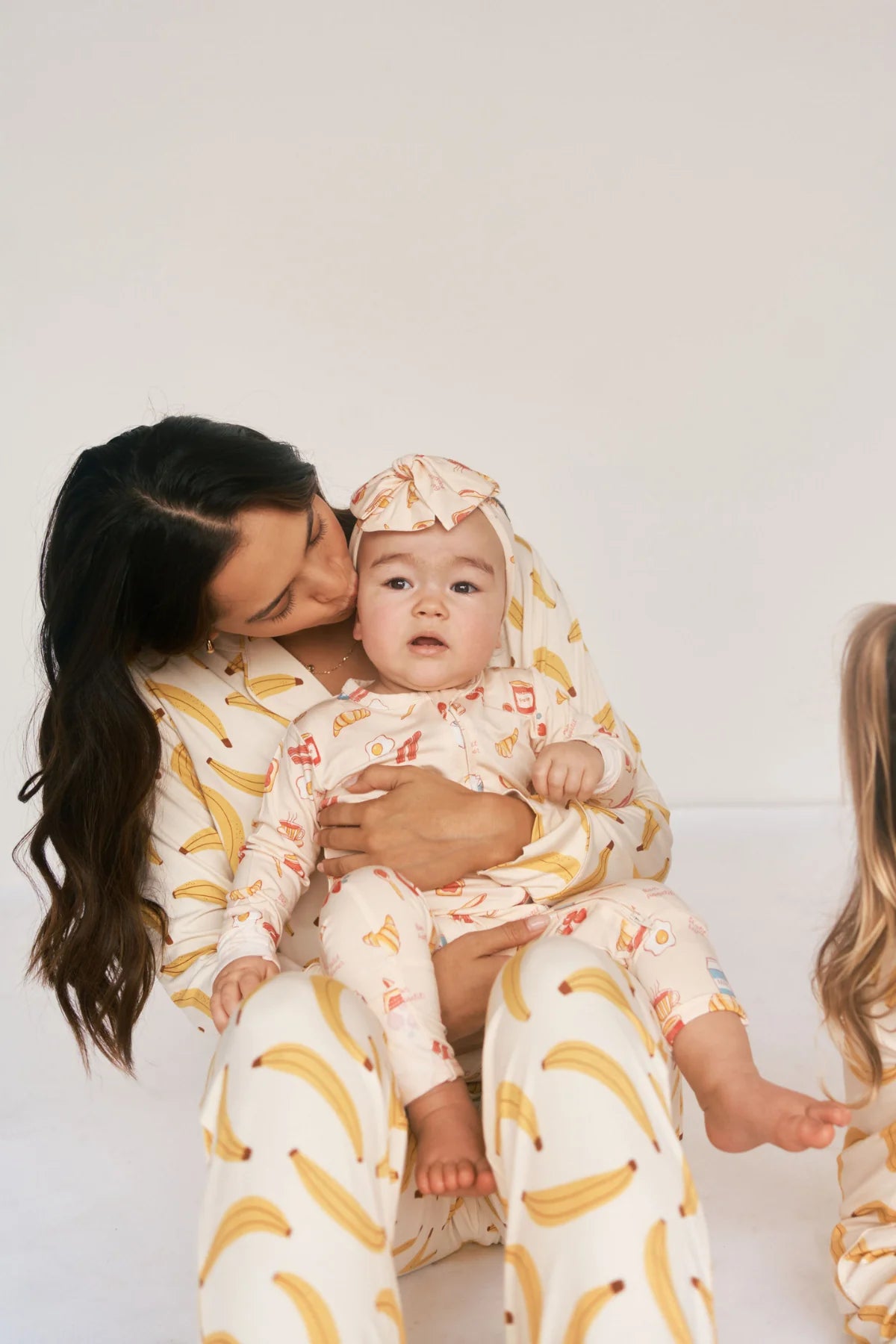
                  
                    Person holding child in a printed sleeper with a white background. 
                  
                