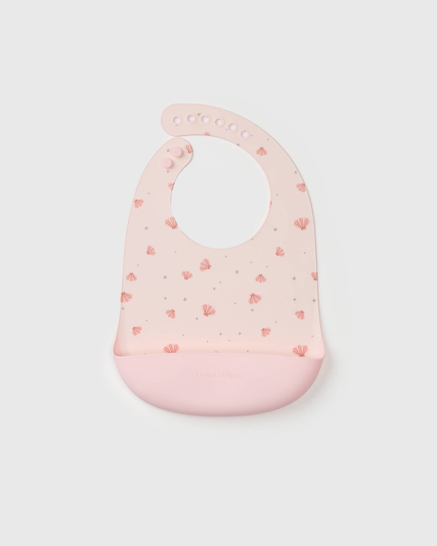 Pink baby silicone bib with seashell pattern on a light gray background.