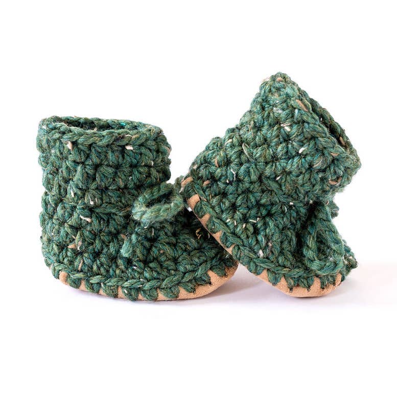
                  
                    A pair of handmade green crocheted baby booties with tan soles, displayed on a clean white background.
                  
                