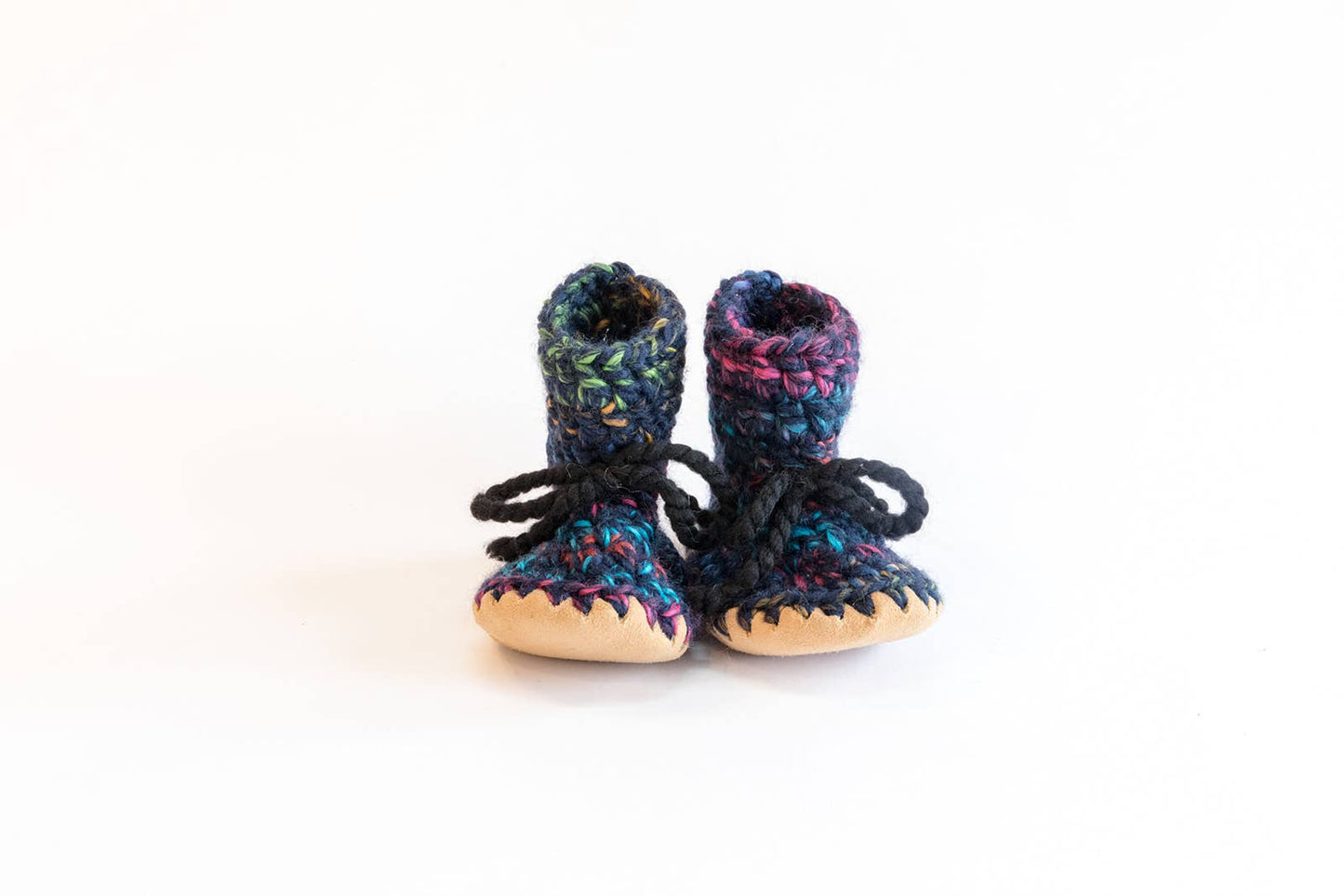 
                  
                    A pair of handmade crochet booties with a multicolor pattern of blue, purple, and green yarn, featuring black laces and natural beige soles, set against a plain white background.
                  
                