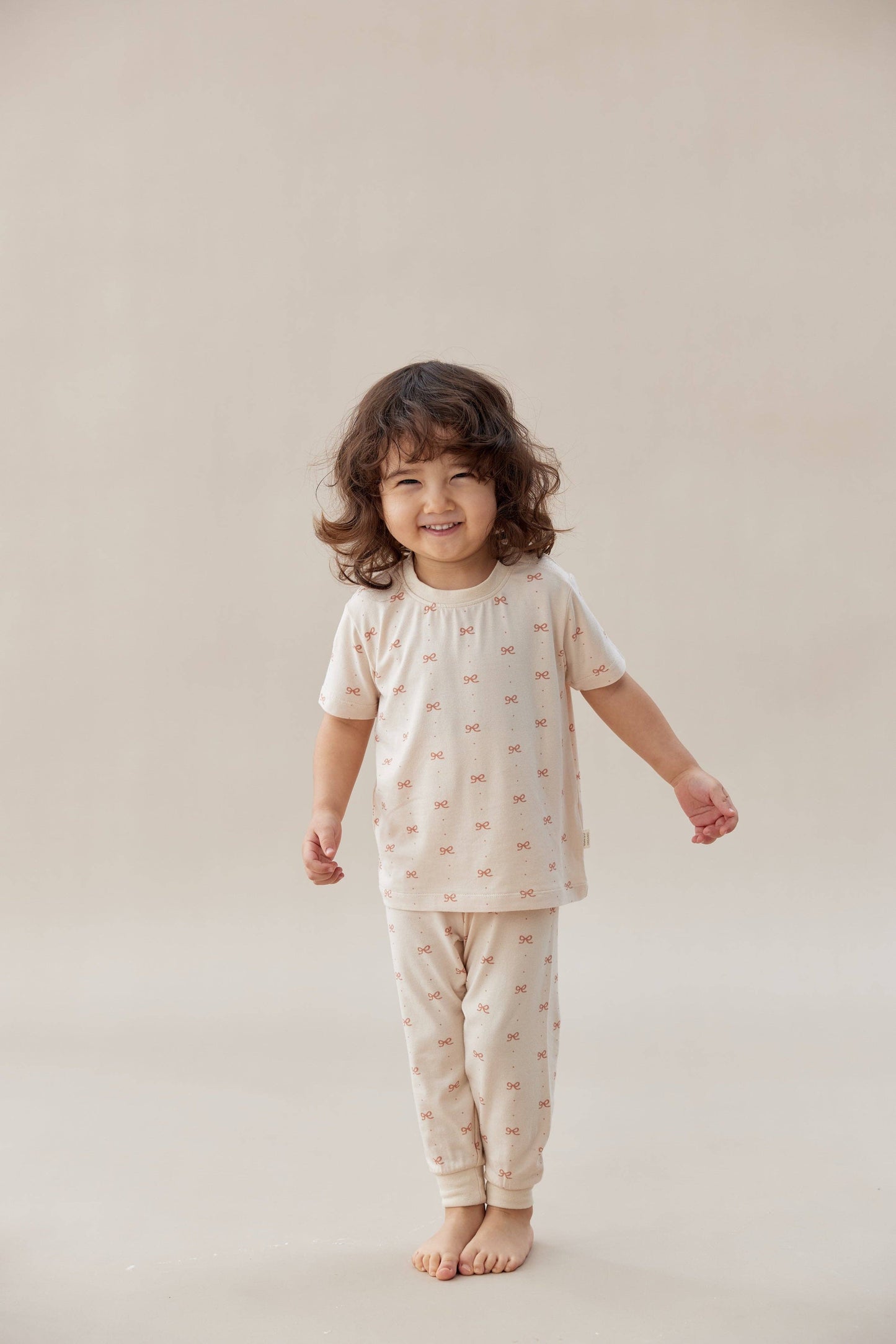 Child wearing a matching pajama set with small patterns on a plain background.
