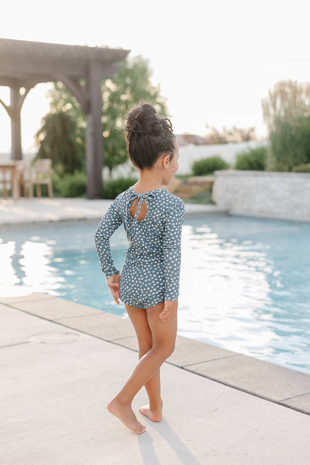 
                  
                    Child in a polka dot swimsuit standing by a pool
                  
                