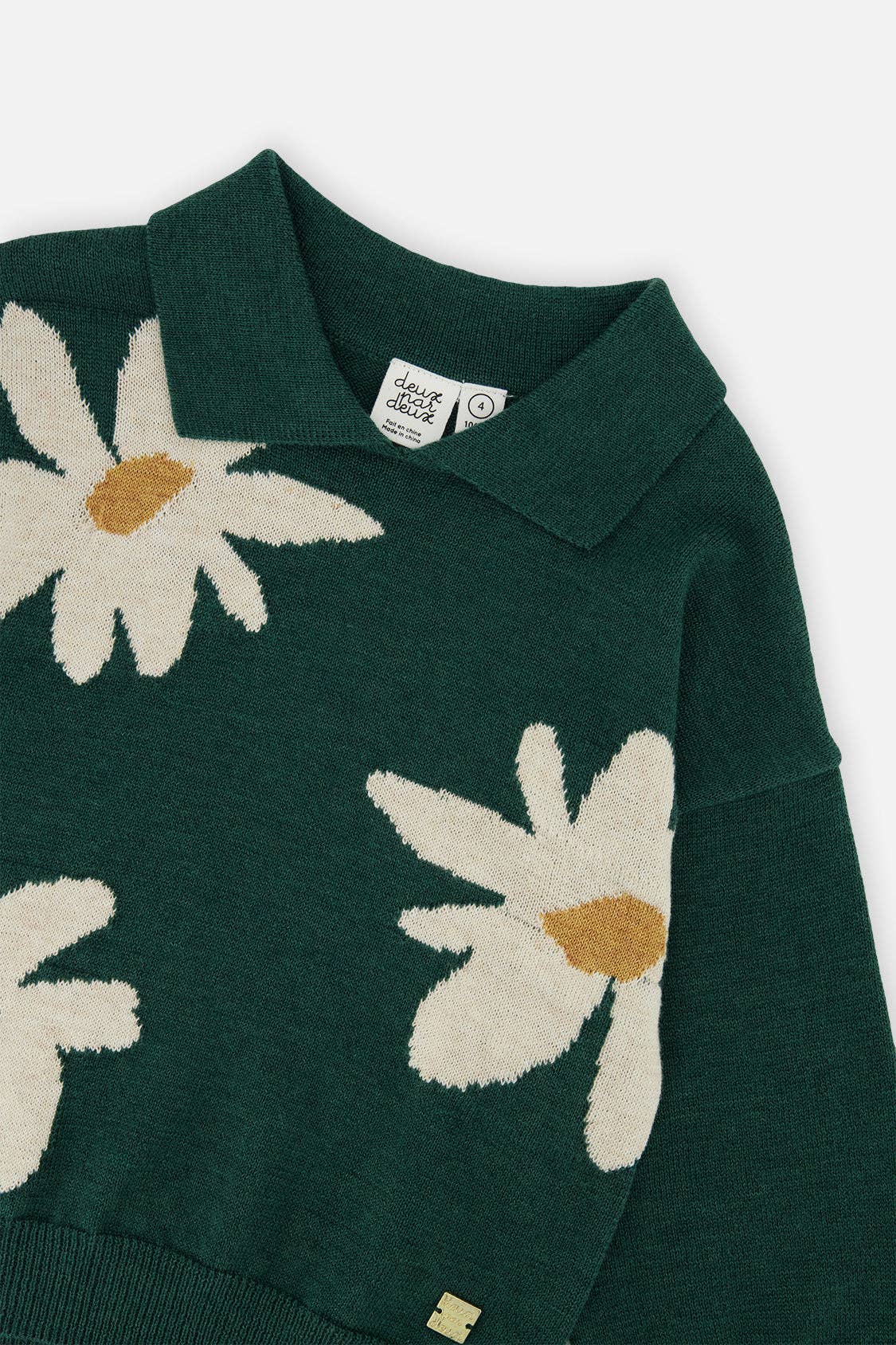 
                  
                    Green sweater with white daisy patterns on a white background.
                  
                