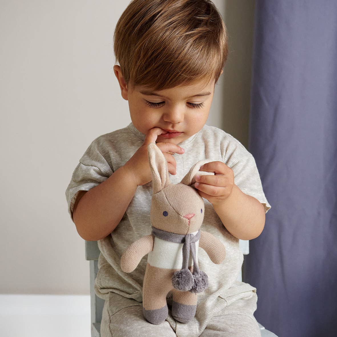 
                  
                    Child holding a plush bunny toy in a neutral setting.
                  
                