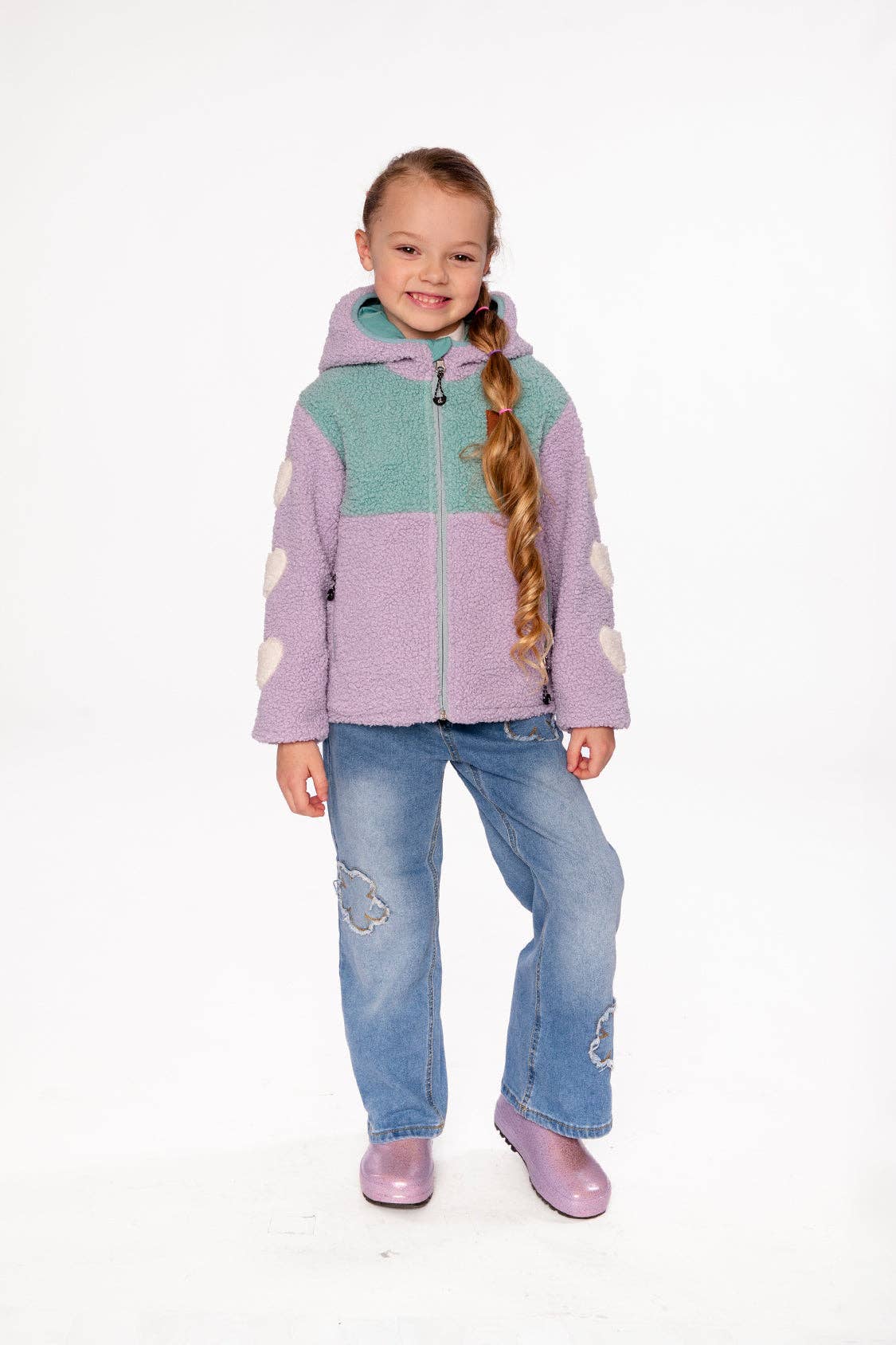 
                  
                    Young girl wearing a colorful jacket and jeans on a white background.
                  
                
