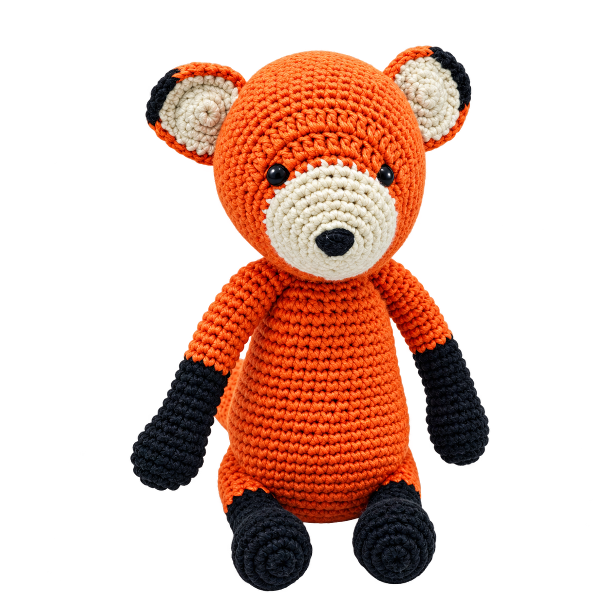 A crocheted plush toy fox in bright orange with cream-colored snout and ears, and black paws and feet, shown against a plain white background.