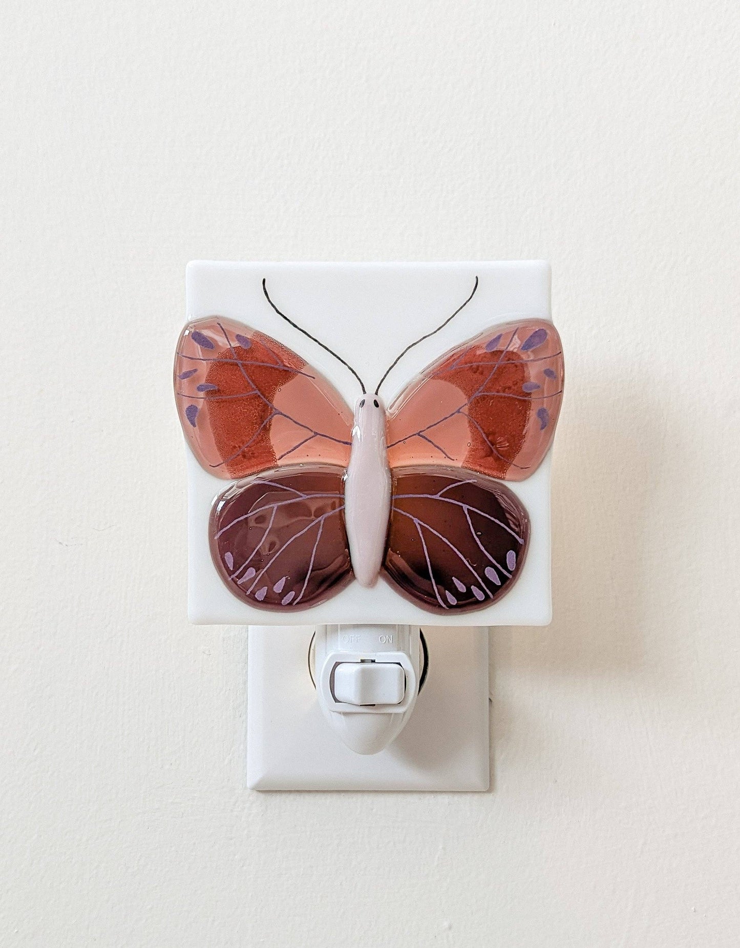 
                  
                    Butterfly-shaped night light on a white wall.
                  
                