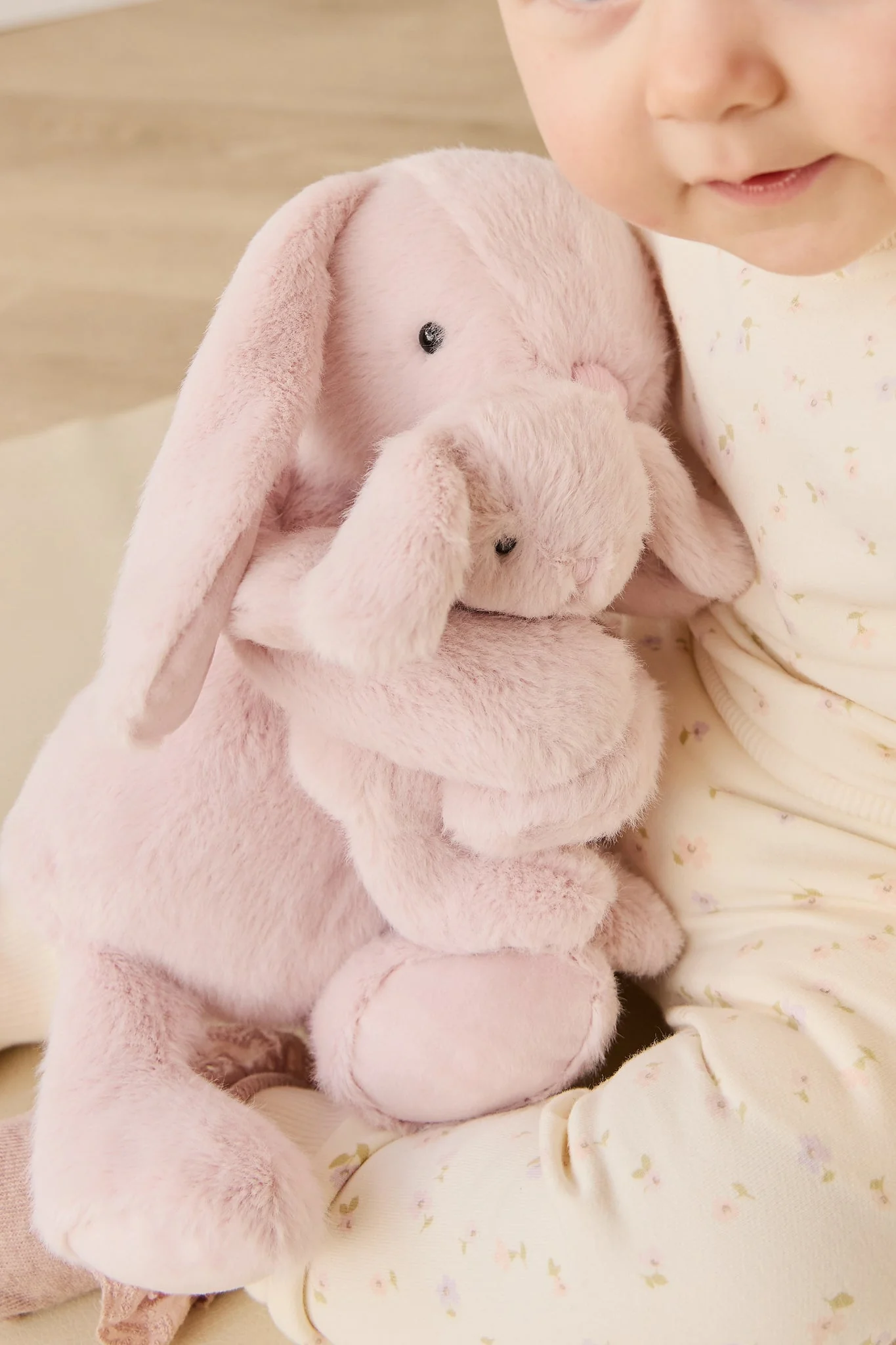 
                  
                    Child holding a pink plush bunny toy with a soft background.
                  
                