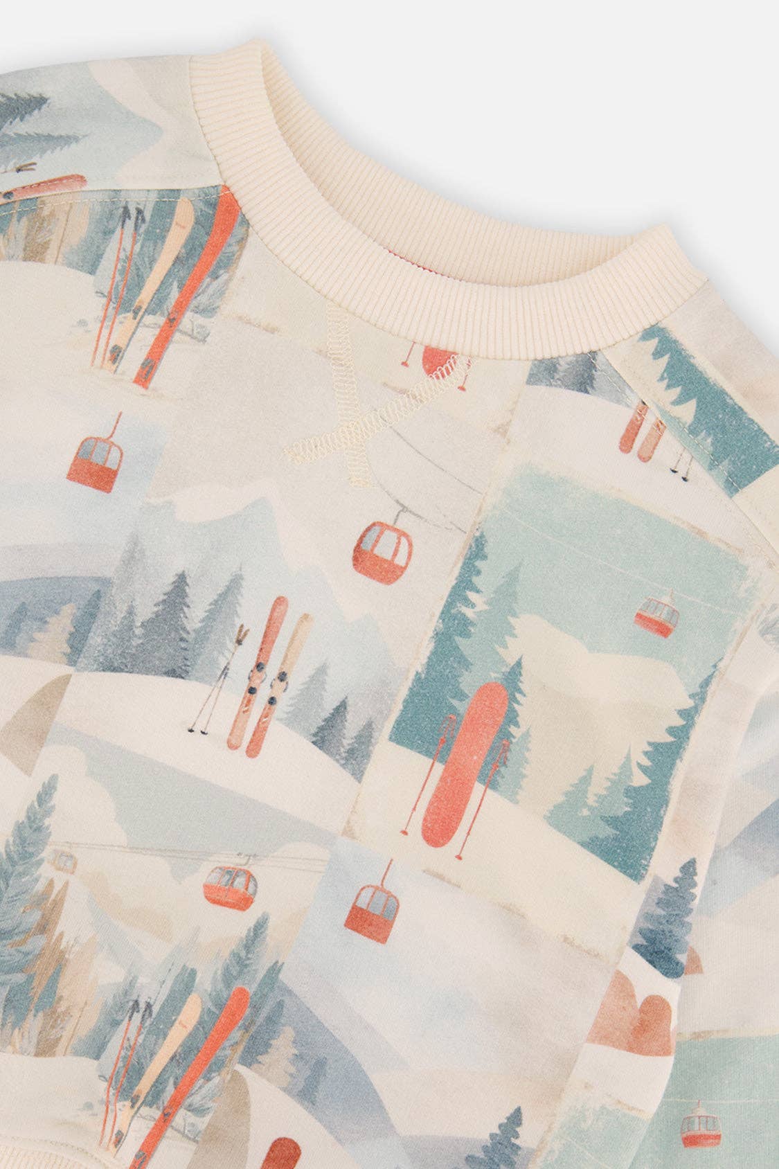 
                  
                    Close-up of a sweater with a ski resort pattern featuring skiers, ski lifts, and trees.
                  
                