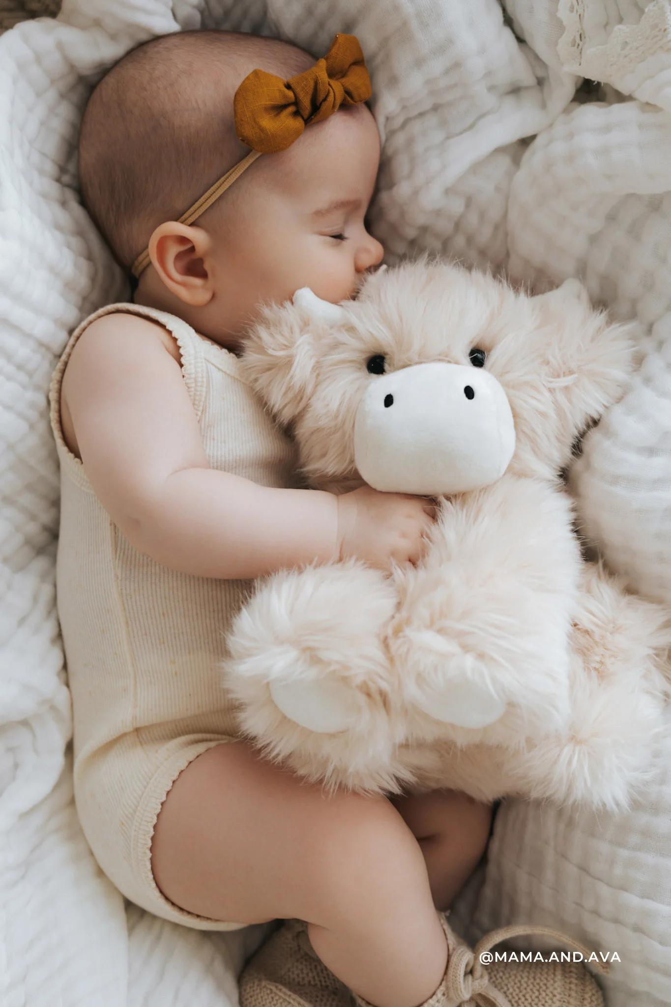 
                  
                    Baby sleeping with a plush cow on a soft blanket.
                  
                