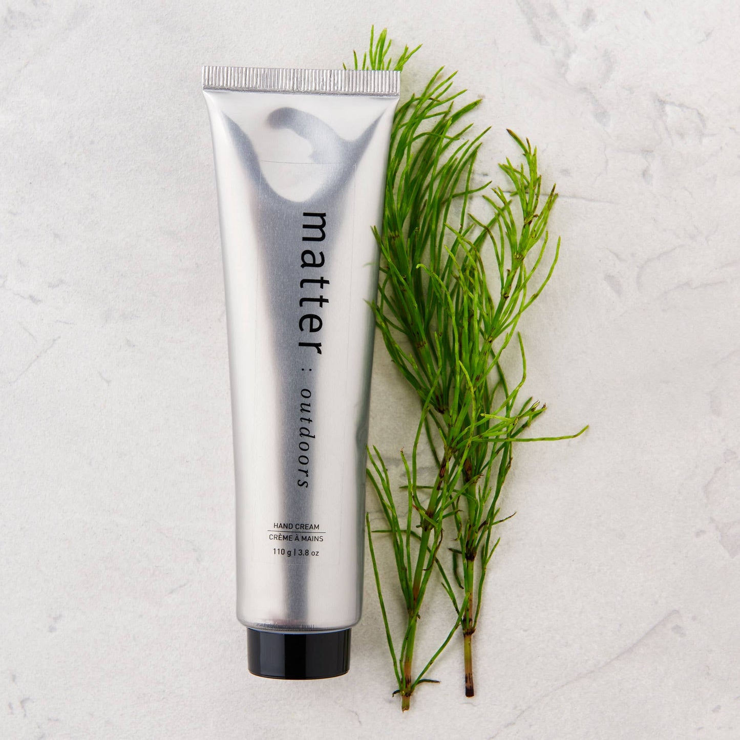 
                  
                    Silver tube of hand cream labeled 'matter' with green plant on a light gray background
                  
                