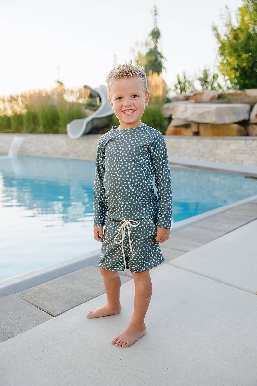 Child wearing a polka dot swimsuit by a pool