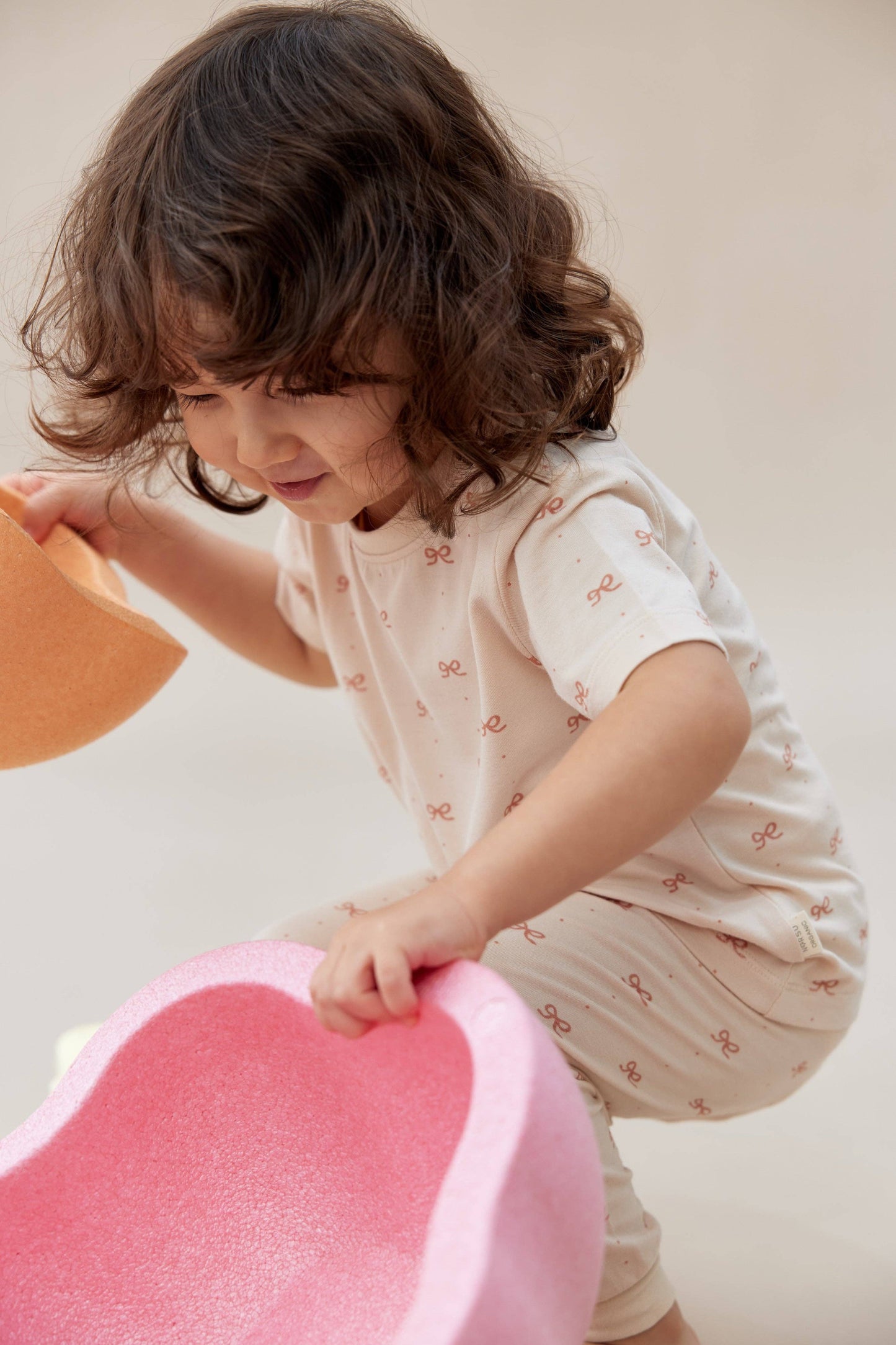
                  
                    Child playing with a pink toy on a light background.
                  
                