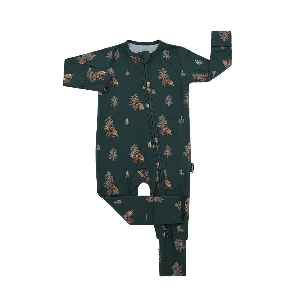 
                  
                    A long-sleeve baby footed sleeper in dark forest green with an all-over print of pine trees and owls, featuring a front zipper closure.
                  
                