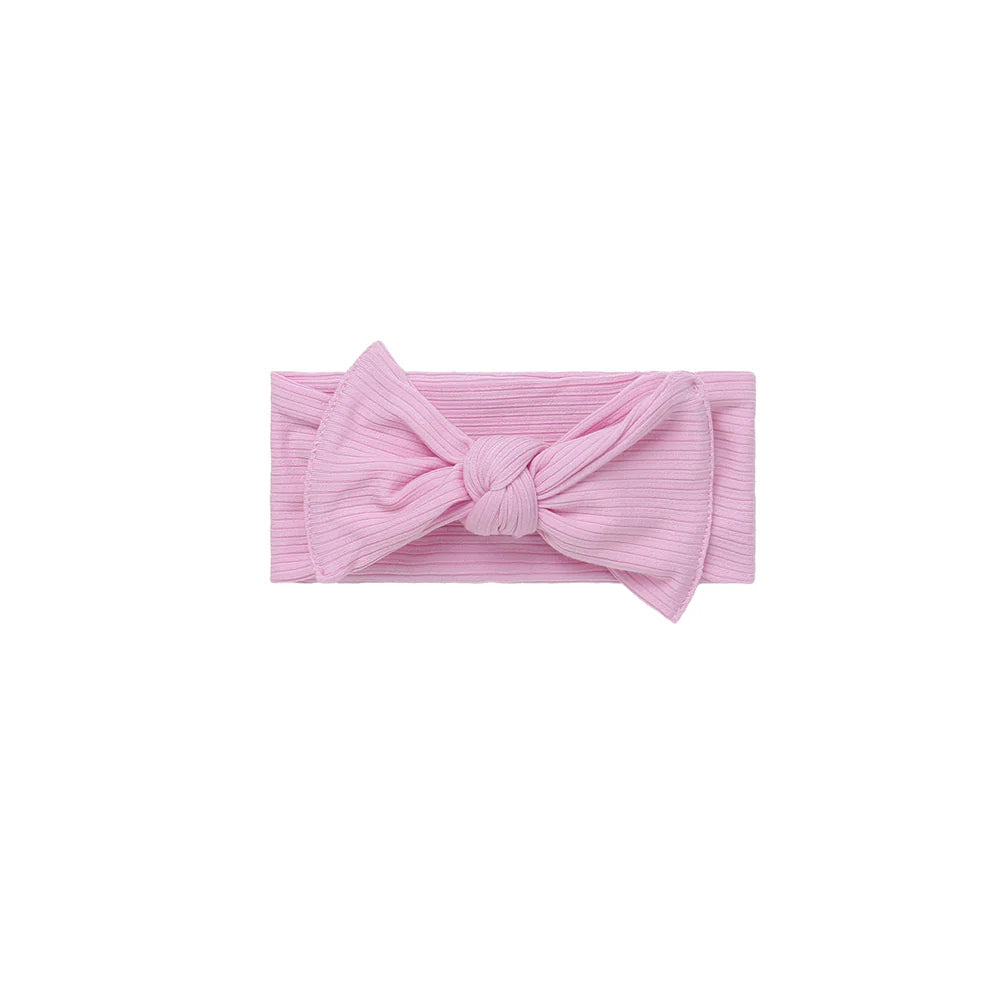 Pink ribbed headband with a bow on a white background