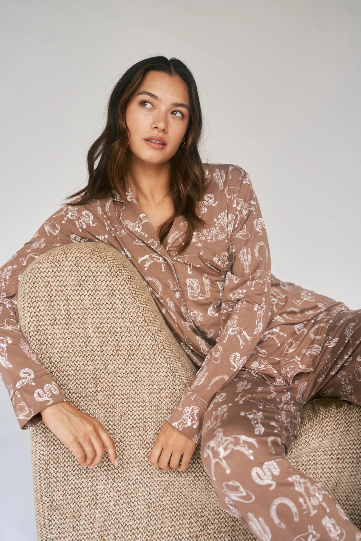 
                  
                    Woman wearing a patterned pajama set sitting on a textured chair against a plain background.
                  
                