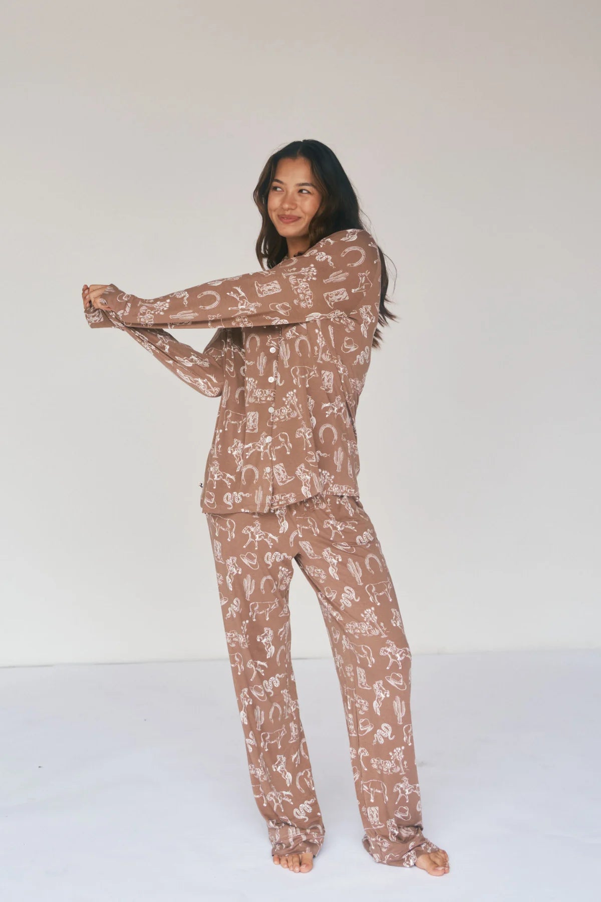 
                  
                    Woman wearing a brown pajama set with white patterns on a white background.
                  
                