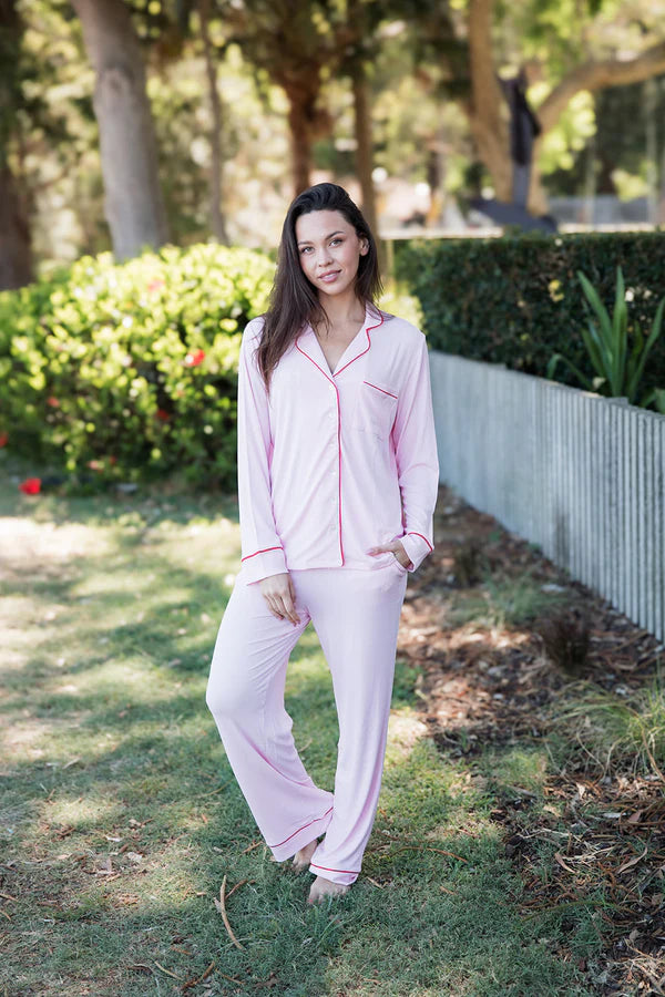 Woman wearing pink pajamas standing outdoors in a garden.