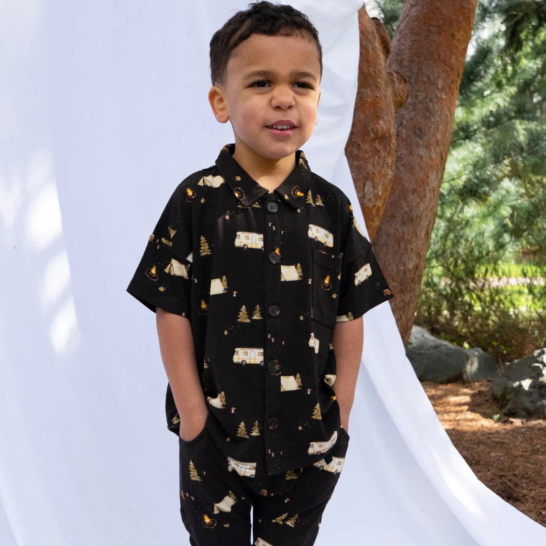 
                  
                    Child wearing a button up polo shirt with a white background. 
                  
                