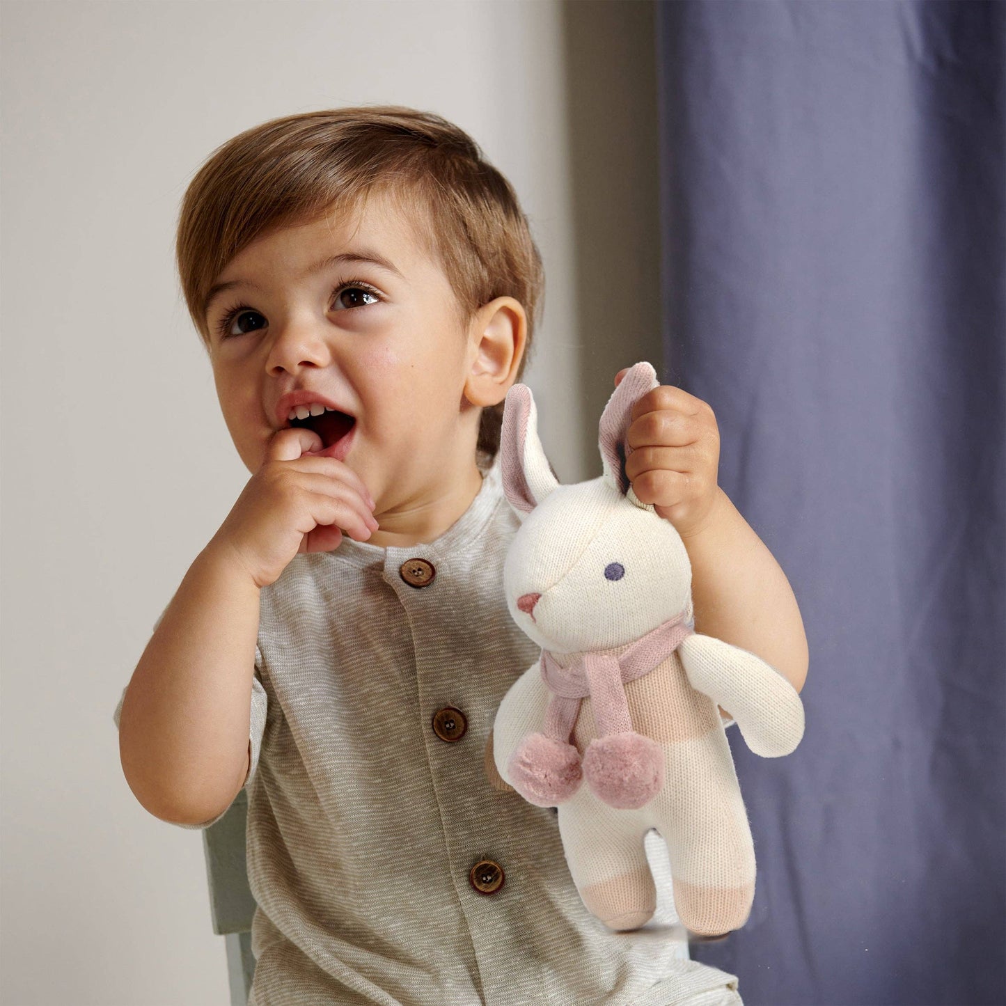 
                  
                    Child holding a plush toy with a neutral background.
                  
                