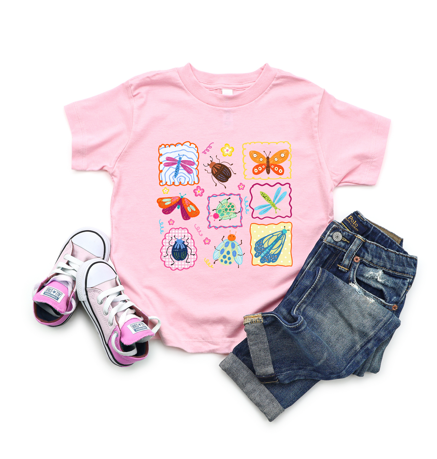 
                  
                    Pink t-shirt with colorful insect designs, paired with jeans and shoes on a white background.
                  
                