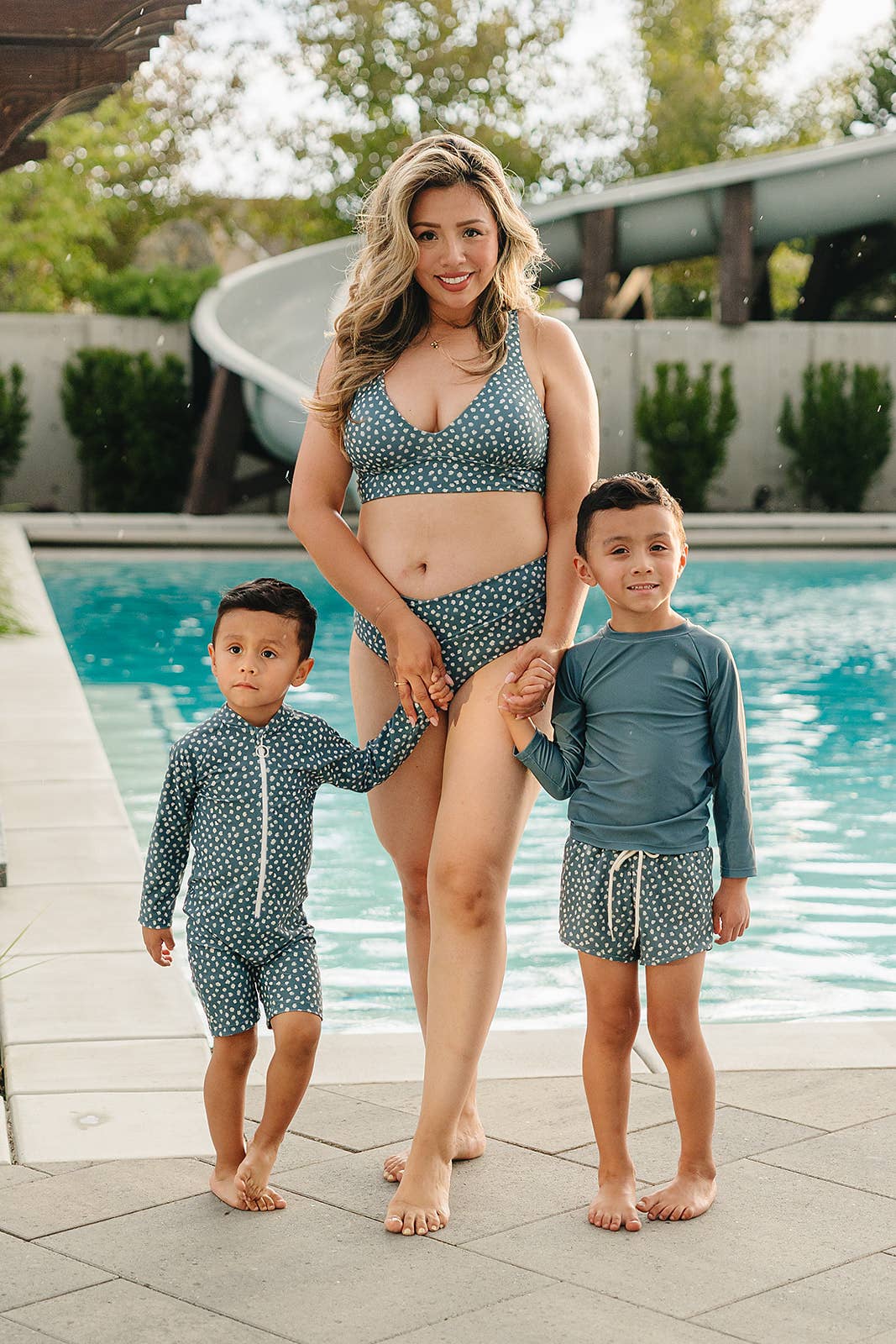 
                  
                    Woman and two children in matching blue polka dot swimwear standing by a pool.
                  
                