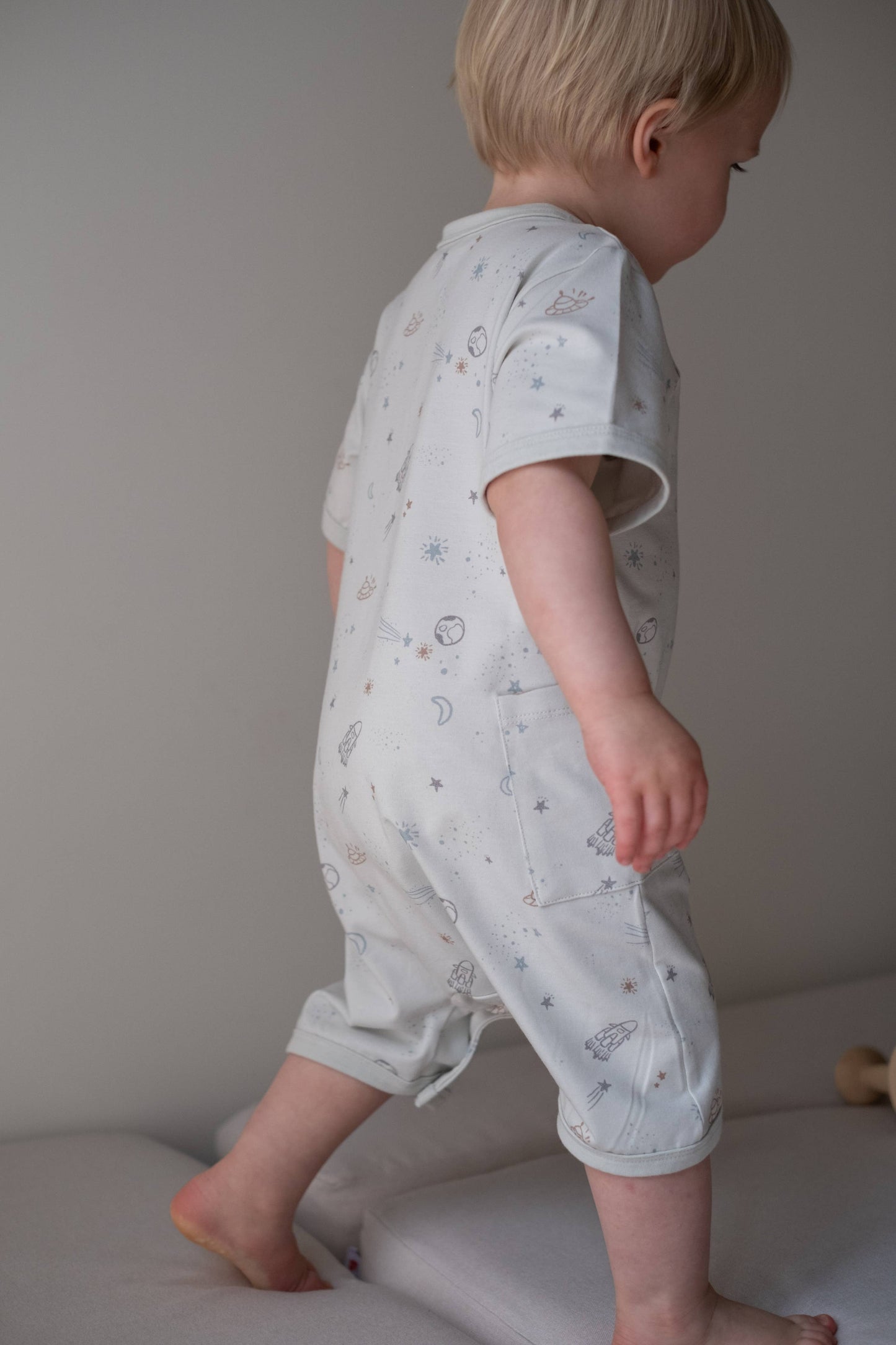 
                  
                    Child wearing a light blue onesie with star pattern on a neutral background.
                  
                