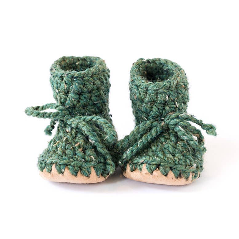 
                  
                    A pair of handmade green crocheted baby booties with beige soles and matching rope laces, photographed on a clean white background.
                  
                