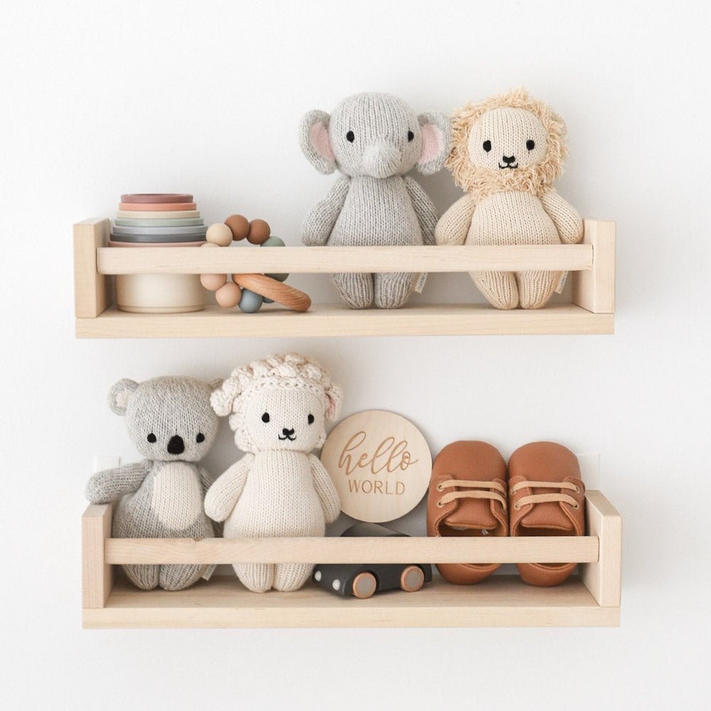 Two bookshelves adorned with adorable hand-knit dolls and a variety of engaging baby toys.