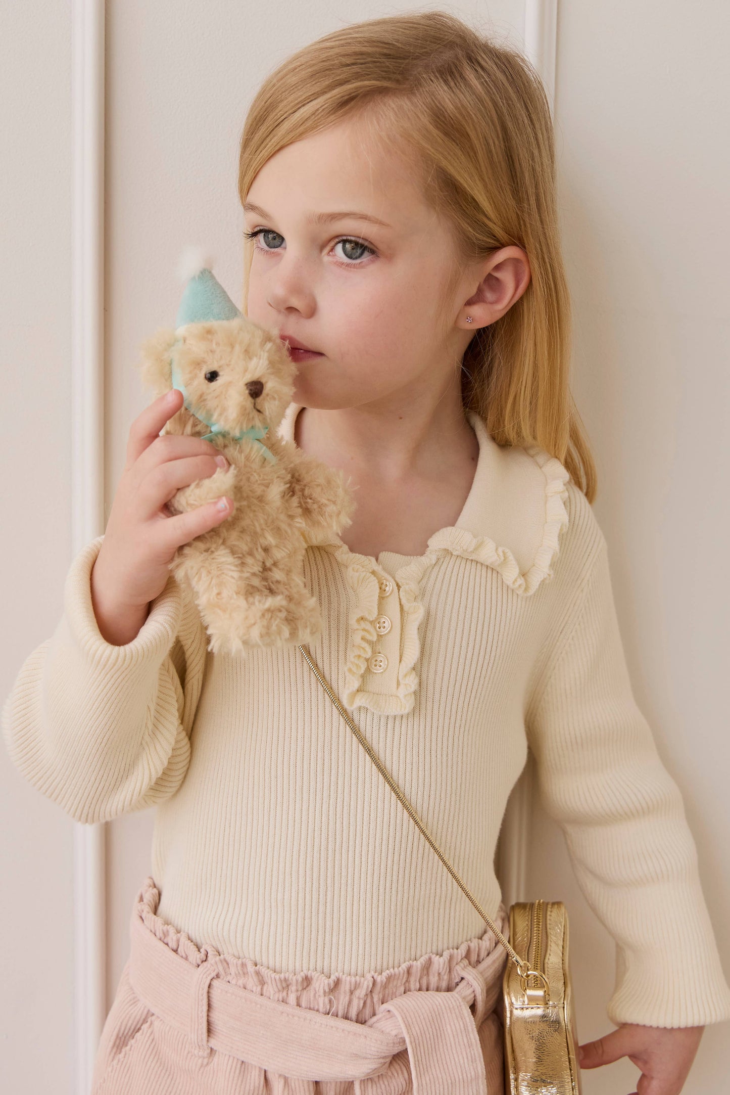 
                  
                    Young girl holding a teddy bear against a white background.
                  
                