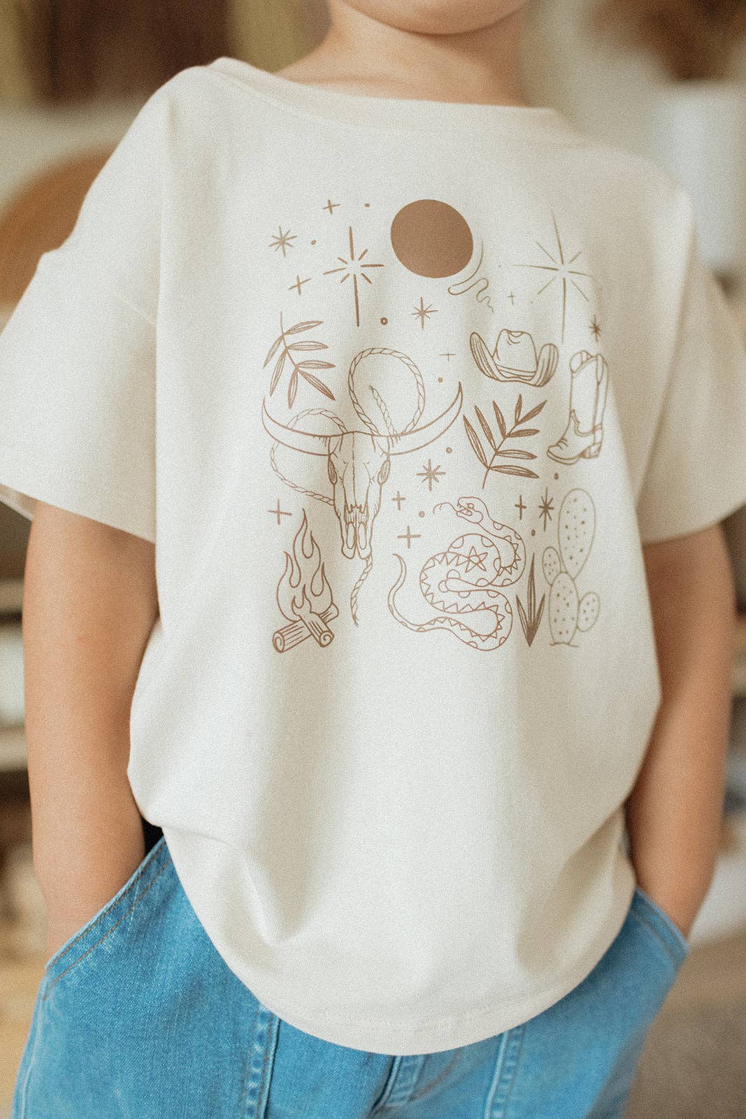 
                  
                    Person wearing a white t-shirt with a graphic design, standing indoors.
                  
                