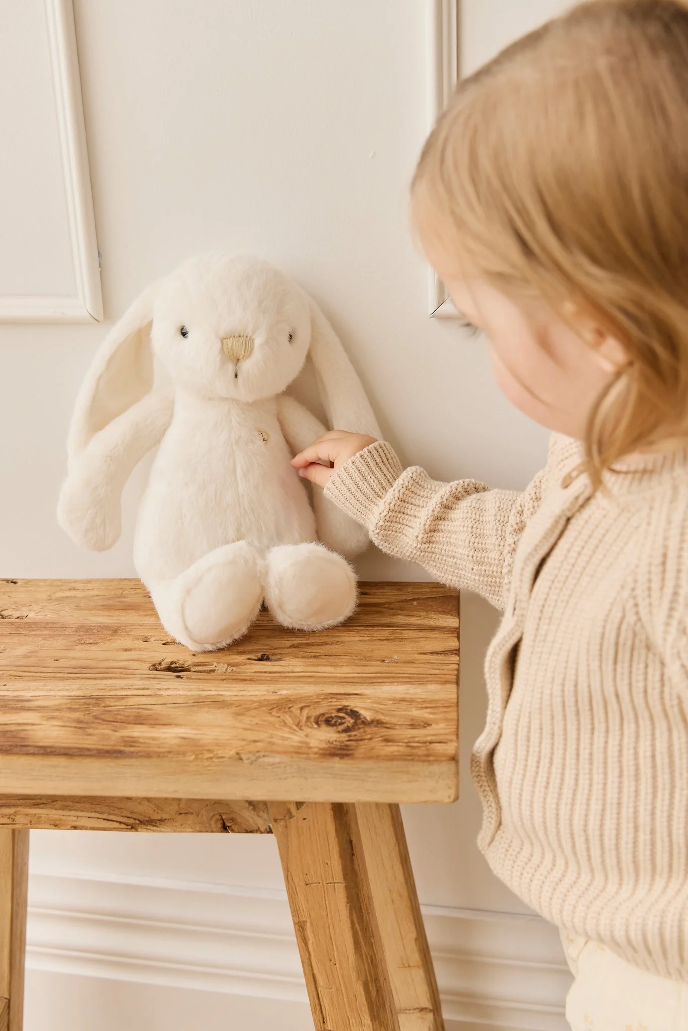 
                  
                    Child interacting with a plush bunny toy on a wooden table.
                  
                