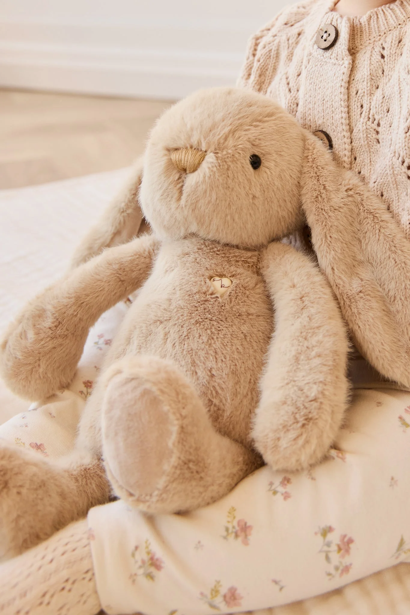 
                  
                    Plush bunny toy on a floral blanket with a soft focus background.
                  
                