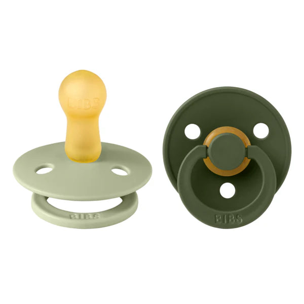 Two baby pacifiers, one beige and green, the other olive green, on a white background.
